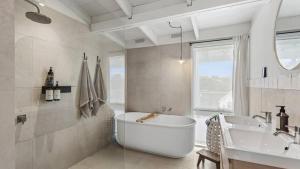 a white bathroom with a tub and a sink at Malmsbury Cottage in Malmsbury