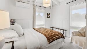 a white bedroom with a bed and a chair at Malmsbury Cottage in Malmsbury