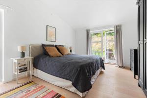 a white bedroom with a bed and a window at 823-Tisvildeleje-Vibevaenget-13-A in Tisvildeleje