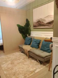 a living room with a couch with blue pillows at TuksHotel in Manila +1 photo