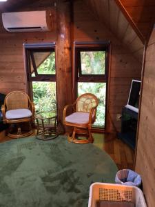 a room with chairs and a tv in a cabin at PrivateVillaHutamiLog in Nago