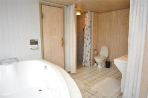 a bathroom with a bath tub and a toilet at 40703-Ulfborg-Helmklit-227 in Ulfborg +17 photos