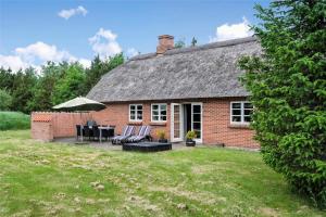 a brick house with a table and chairs and an umbrella at 10820-Ulfborg-Baekbyvej-113 in Ulfborg