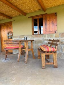 a table and two benches in front of a building at Vogelsang Farm Cottage in Oudtshoorn