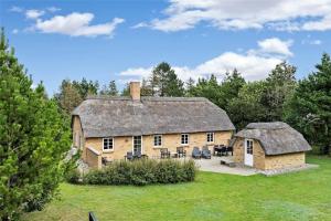 a large stone house with a thatched roof at 30859-Ulfborg-Bellisvej-432 in Ulfborg