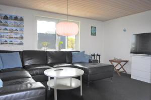 a living room with a black leather couch and a table at 70029-Ulfborg-Vesterhavsgade-6 in Ulfborg