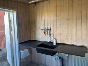 a kitchen with a black sink and wooden walls at 70099-Ulfborg-Klitrosevej-2 in Ulfborg +16 photos