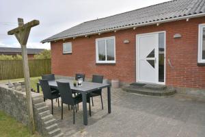 a patio with a table and chairs in front of a house at 70099-Ulfborg-Klitrosevej-2 in Ulfborg