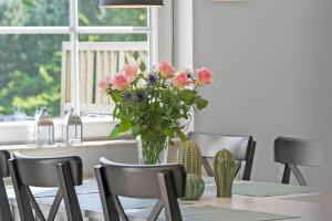 a dining room table with a vase of pink flowers at 30876-Ulfborg-Krogsgardvej-5 in Ulfborg