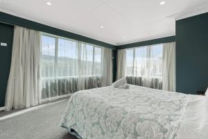 a bedroom with a bed and large windows at Roslyn Sanctuary Hereford St Dunedin in Dunedin