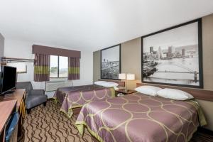 a hotel room with two beds and a flat screen tv at Super 8 by Wyndham Bedford in Bedford