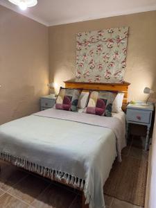 a bedroom with a large bed with two night stands at Vogelsang Farm Cottage in Oudtshoorn
