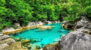 a blue pool of water with rocks and trees at Casa Versini in Balogna