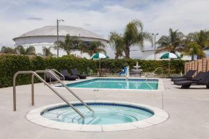 a swimming pool with chairs and a building in the background at Days Inn & Suites by Wyndham South Gate in South Gate