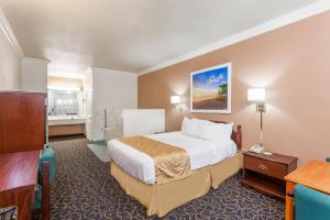a hotel room with a bed and a television at Days Inn & Suites by Wyndham South Gate in South Gate +9 photos