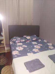 a bed with a blue blanket with flowers on it at Sumud Bonda Homestay in Kuala Kerai