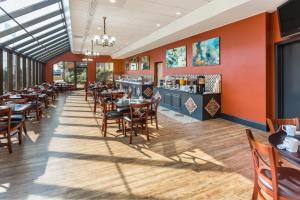 a dining room with tables and chairs and a bar at Wyndham Garden Greensboro in Greensboro