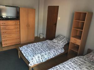 a bedroom with two beds and a dresser and a tv at Noclegi Ściegiennego in Sosnowiec