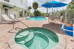 a small pool with a table and an umbrella at Days Inn & Suites by Wyndham Fort Pierce I-95 in Fort Pierce