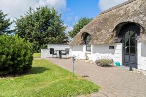a thatch roofed house with a table and chairs at 20135-Ulfborg-Fyrrebakken-7 in Ulfborg