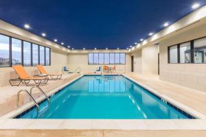 a pool with blue water in a building with windows at Wingate by Wyndham Lubbock in Lubbock