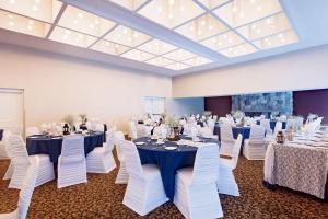 a banquet hall with tables and white chairs at Ramada by Wyndham Pinewood Park Resort North Bay in North Bay