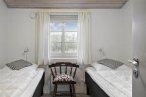a bedroom with two beds and a chair and a window at 20723-Ulfborg-Sortebaervej-1 in Ulfborg