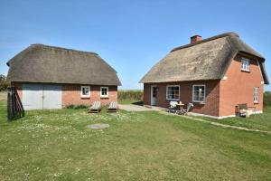a barn with a thatched roof and two benches in a yard at 20202-Ulfborg-Husby-Klitvej-15 in Ulfborg
