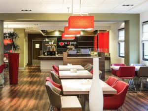 a restaurant with white tables and red chairs at Hotel Ibis Milano Malpensa in Cardano al Campo