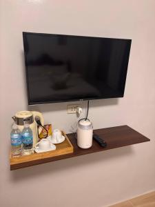 a flat screen tv on a wall with a shelf at Perrera Guesthouse in Santa Ana