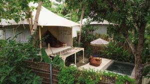 a woman sitting in front of a tent in a garden at Exotic private glamping in Nusa Penida