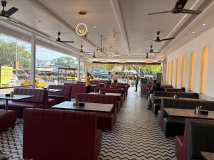 a restaurant with tables and chairs and people in the background at Hotel Mathura Inn Shirdi in Shirdi
