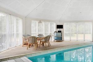 a dining room with a table and chairs next to a pool at 80608-Vemb-Knudehus-51 in Vemb
