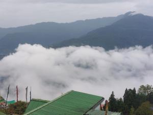 a view of a mountain covered in clouds with a green roof at Hotel white lion-Near Bhajra Taxi Stand in Gangtok +18 photos
