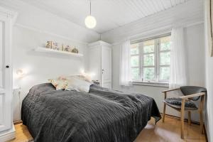 a bedroom with a bed and a chair and windows at 10173-Ulfborg-Gaffelbjergvej-24 in Ulfborg