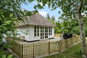 a white cottage with a thatched roof and a fence at 10173-Ulfborg-Gaffelbjergvej-24 in Ulfborg