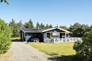 a blue house with a white fence in a yard at 30826-Ulfborg-Klovervej-480 in Ulfborg