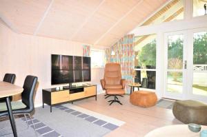 a living room with a television and a chair at 30070-Ulfborg-Klovervej-478 in Ulfborg