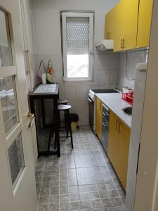 a small kitchen with a table and yellow cabinets at APARTMANI SARA in Valjevo
