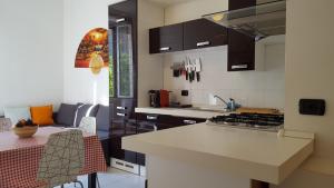 ミラノにあるBnButler - Sempione Apartment - MiCoのキッチン(黒いキャビネット、カウンタートップ付)