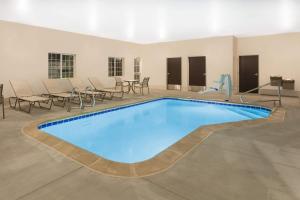 a pool in a room with chairs and tables at Microtel Inn & Suites by Wyndham Springville in Springville