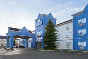 a blue building with a tree in front of it at Days Inn & Suites by Wyndham Brooks in Brooks
