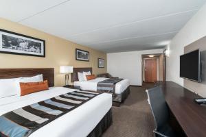 a hotel room with two beds and a desk at Wingate by Wyndham Bowling Green in Bowling Green