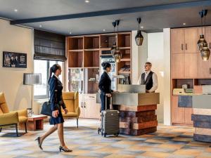 a group of people standing around a counter with luggage at Mercure Hotel Mannheim am Rathaus in Mannheim