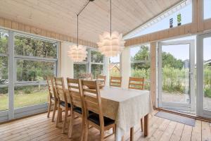 a dining room with a table and chairs and windows at 30185-Ulfborg-Bellisvej-509 in Ulfborg