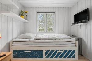 a bed in a room with a window and a television at 30185-Ulfborg-Bellisvej-509 in Ulfborg