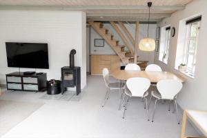 a dining room with a table and chairs and a stove at 10294-Ulfborg-Gaffelbjergvej-44 in Ulfborg