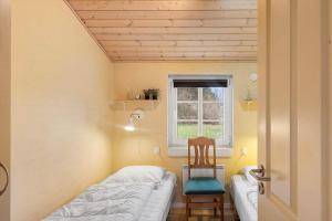 a room with a bed and a chair and a window at 30848-Ulfborg-Valmuevej-286 in Ulfborg