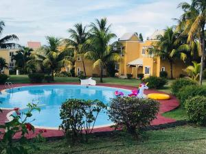 a swimming pool in a yard with palm trees at Secure villa in a quiet garden with pool in Albion