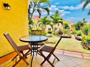 a table and chairs on a balcony with a view of a yard at Secure villa in a quiet garden with pool in Albion